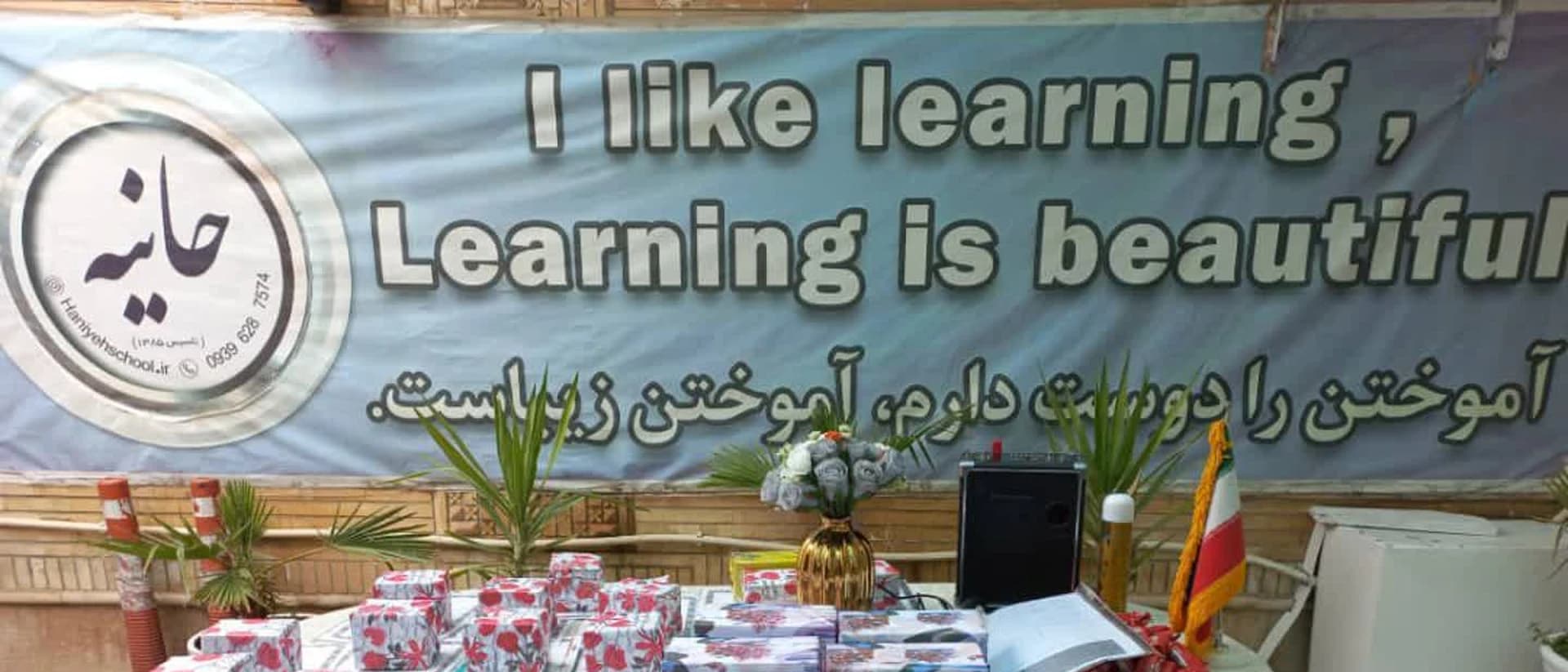 میز خوشآمدگویی با بنر «آموختن را دوست دارم» و نشان مجتمع آموزشی حانیه